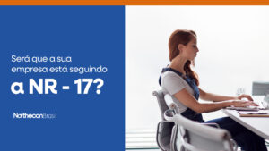Mulher trabalhando em um escritório, sentada de frente para um computador e o seguinte texto: Será que a sua empresa está seguindo a NR-17?