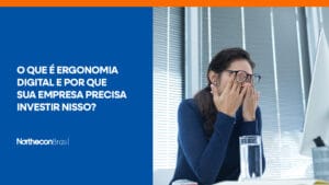 Mulher em frente a um computador da Apple coçando os olhos e o seguinte texto: O que é ergonomia digital e por que sua empresa precisa investir nisso?